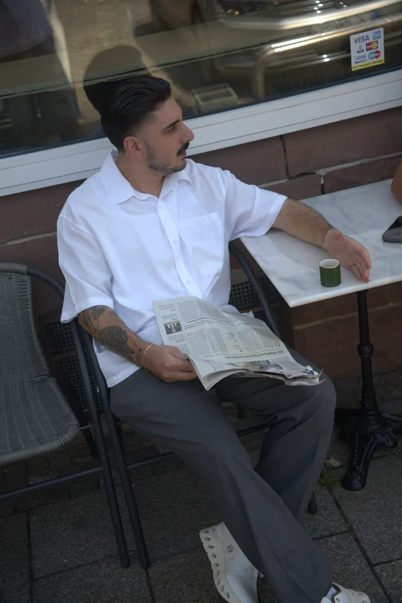 Christopher Keanu Reinhardt liest Zeitung vor dem Salon in der Hauptstraße